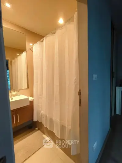 Modern bathroom with shower curtain and sleek vanity in cozy apartment.