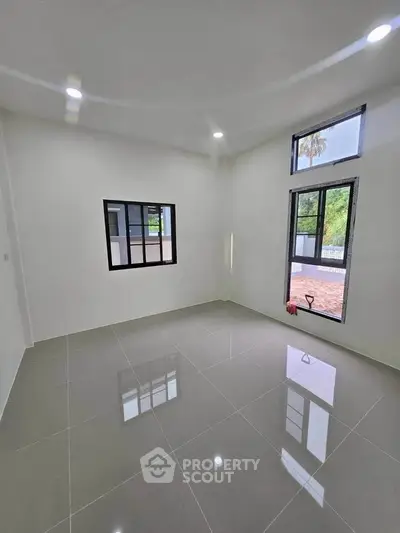 Spacious empty room with large windows and glossy tiled floor, perfect for customization.