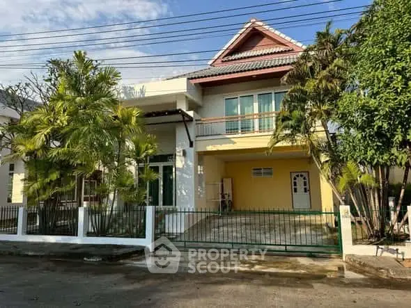 Charming two-story house with lush garden and gated driveway in a serene neighborhood.