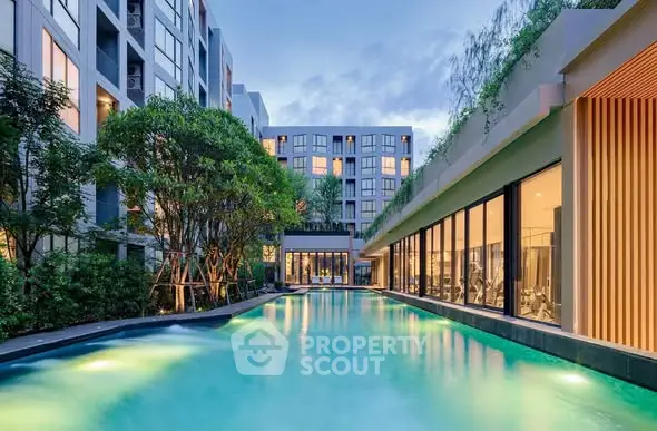 Luxurious apartment complex with stunning pool and modern architecture at dusk.