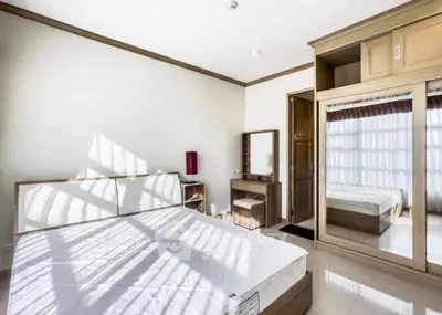 Bright and spacious bedroom with modern furnishings and large mirrored wardrobe.