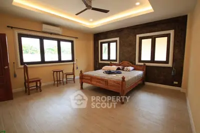Spacious bedroom with wooden furniture and large windows in a modern home.