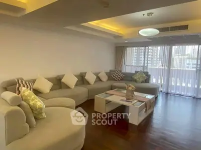 Spacious living room with modern sectional sofa and city view through large windows.