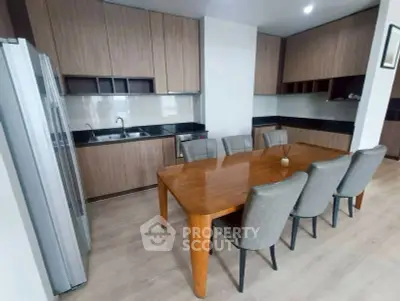 Modern kitchen with wooden cabinets and dining area, featuring sleek design and ample space.