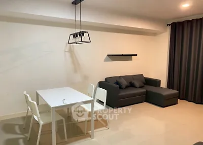 Modern living room with sleek furniture and minimalist design, featuring a cozy sofa and dining area.
