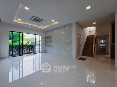 Spacious modern living room with large windows and elegant staircase