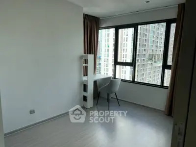 Bright study room with modern desk and chair, large windows offering city view.