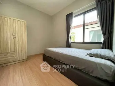 Cozy bedroom with single bed and wardrobe, featuring natural light from large window.