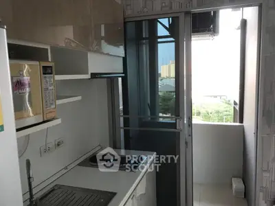 Compact kitchen with modern appliances and balcony view in urban apartment
