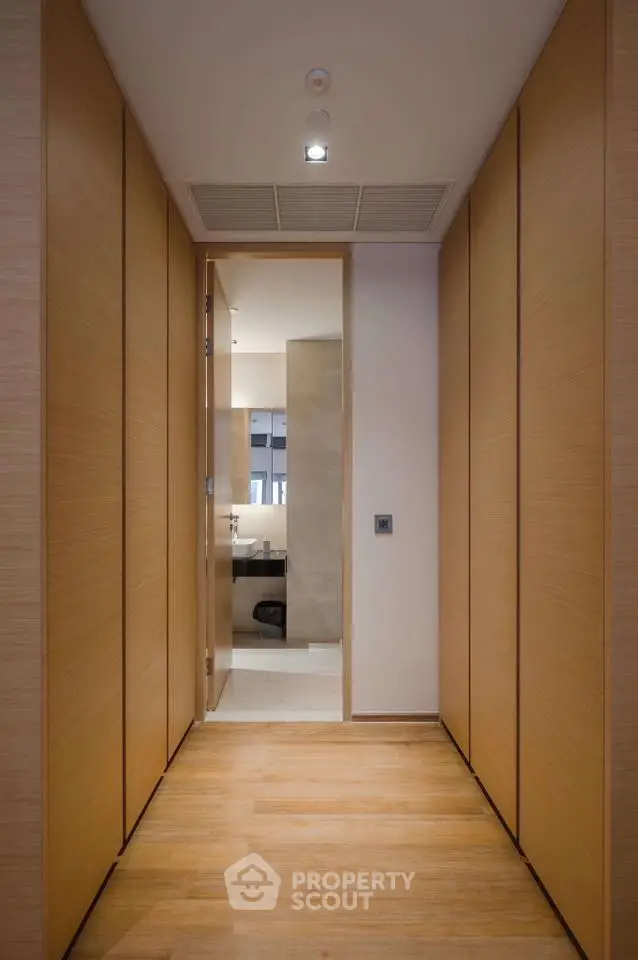 Modern hallway with wooden paneling leading to a sleek bathroom