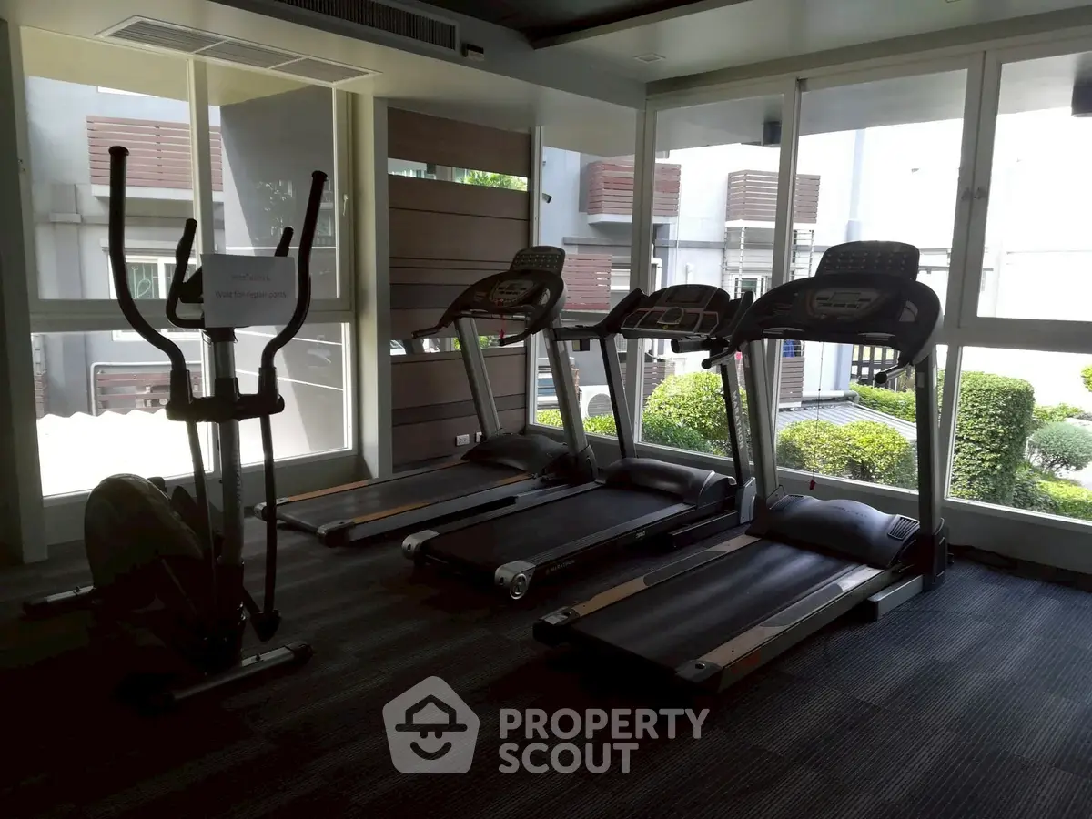 Modern gym with treadmills and elliptical in a bright, windowed room