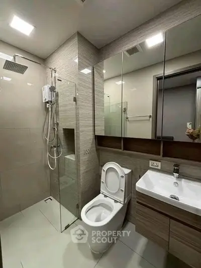 Modern bathroom with glass shower and sleek fixtures in contemporary apartment.