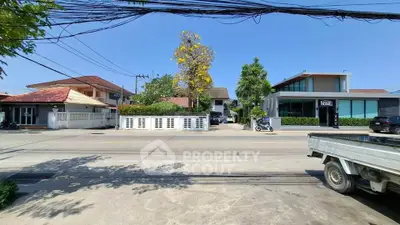 Charming suburban street view with modern and traditional homes under clear blue sky.