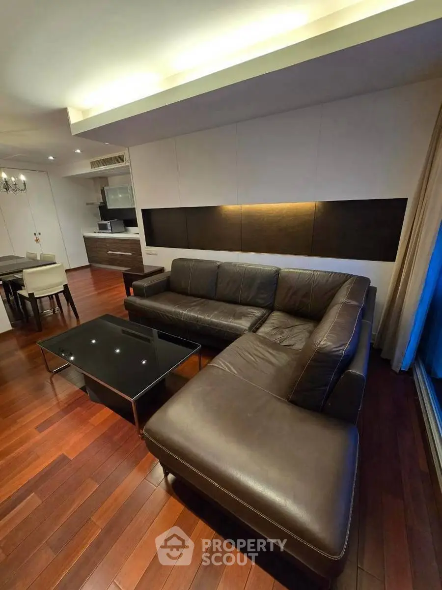 Luxurious living room with sleek leather sofa and modern open kitchen design.