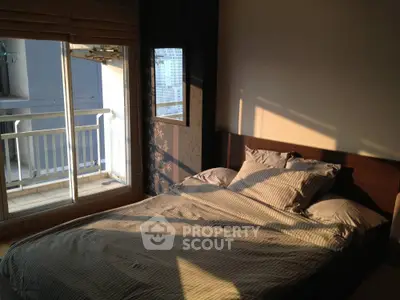 Cozy bedroom with balcony access and city view, perfect for urban living.