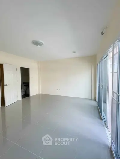 Spacious empty room with large windows and tiled floor, ready for customization.