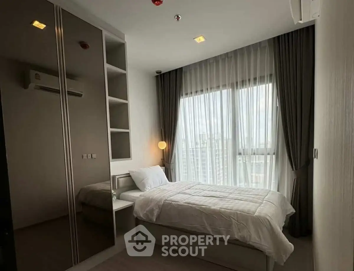 Cozy bedroom with large window and modern furnishings, perfect for urban living.