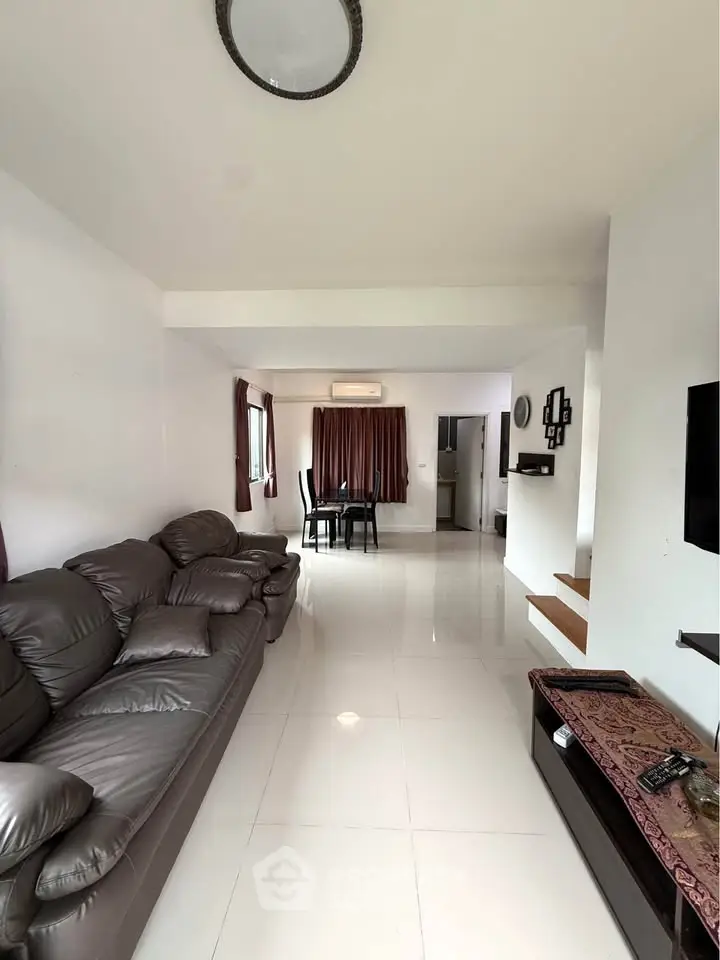 Spacious living room with modern leather sofa and dining area in open layout