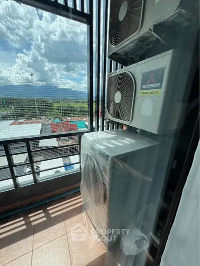 Modern balcony with air conditioning units and scenic view of rooftops and mountains.