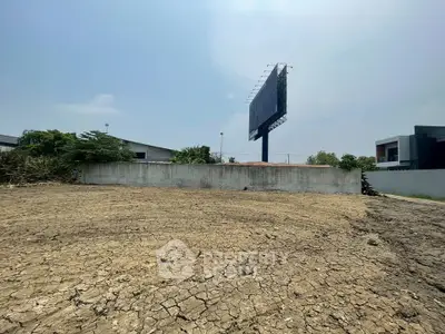 Spacious vacant land plot with potential for development, featuring a clear sky and surrounding buildings.