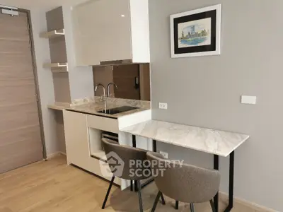 Modern kitchen with sleek design, marble countertops, and cozy dining area in a stylish apartment.
