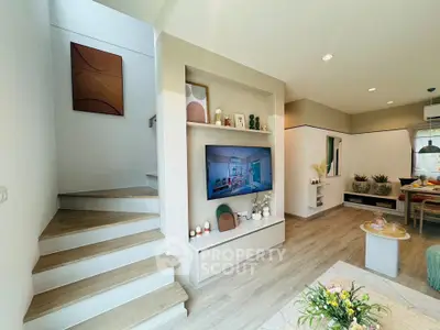 Modern living room with stylish decor and open layout, featuring a built-in TV and cozy dining area.