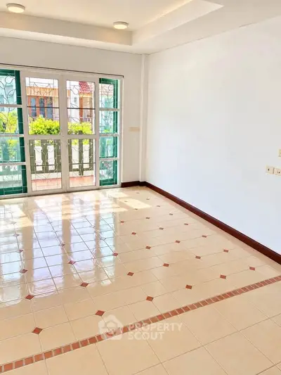 Bright empty room with tiled floor and large windows overlooking a garden.