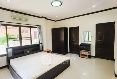 Spacious bedroom with modern furnishings and large window for natural light.
