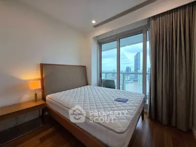 Spacious bedroom with city view and modern furnishings in high-rise apartment.