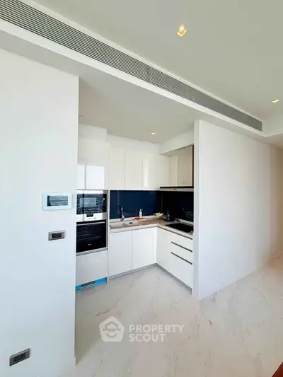 Modern kitchen with sleek white cabinetry and integrated appliances in a bright, open space.