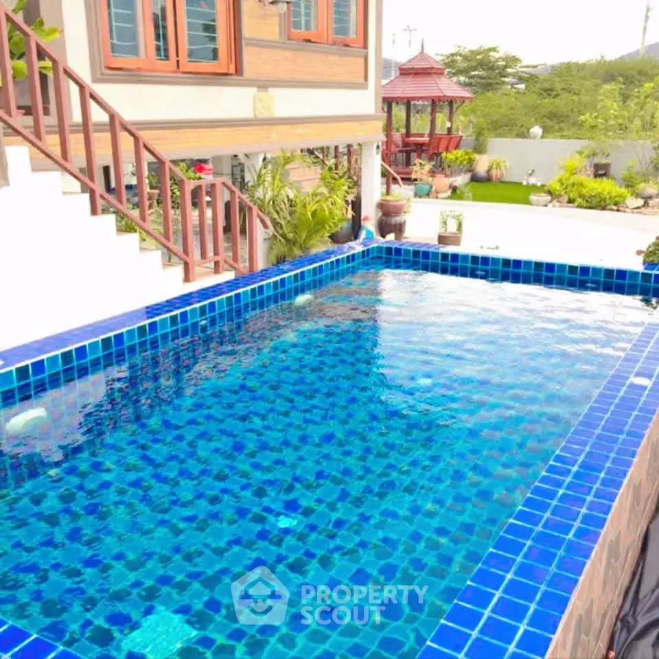 Charming property with a vibrant blue-tiled pool and lush garden, perfect for relaxation and outdoor enjoyment.