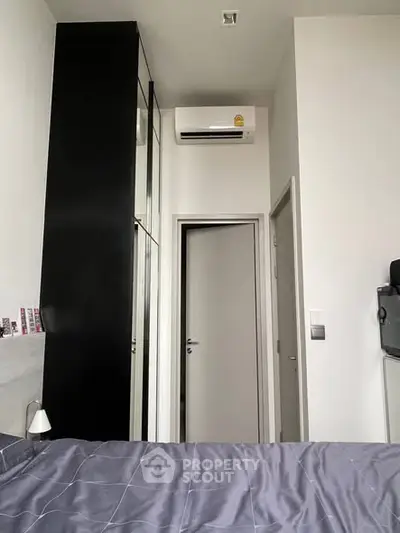 Modern bedroom with air conditioning and sleek black wardrobe