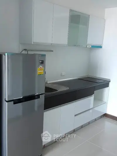 Modern kitchen with sleek cabinetry and stainless steel fridge in a contemporary apartment.