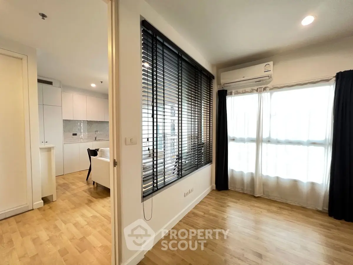Modern apartment interior with open layout and wooden flooring, featuring a bright living area and kitchen.