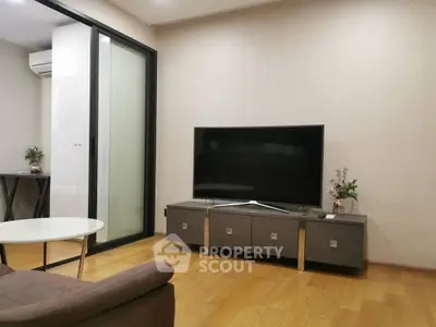 Modern living room with sleek TV stand and wooden flooring, featuring a stylish glass partition.