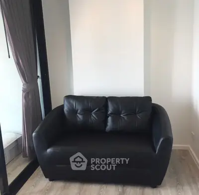 Cozy black leather loveseat in modern apartment with elegant curtains and wooden flooring.