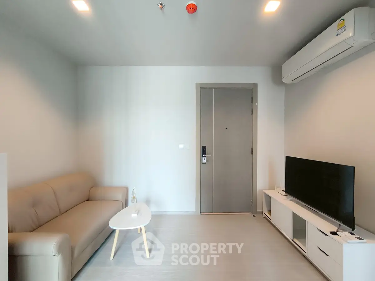 Modern living room with sleek sofa, flat-screen TV, and minimalist decor in a cozy apartment.