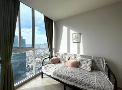 Bright living room with large windows and city view, featuring a cozy sofa and modern decor.