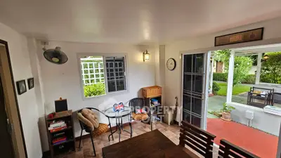 Charming indoor-outdoor living space with garden view and cozy seating area.