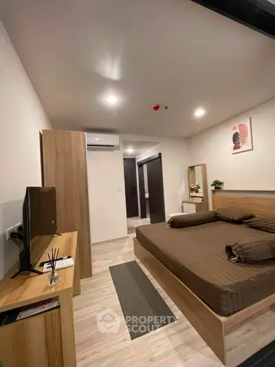 Modern bedroom with stylish decor and wooden furniture, featuring a cozy bed and sleek TV setup.