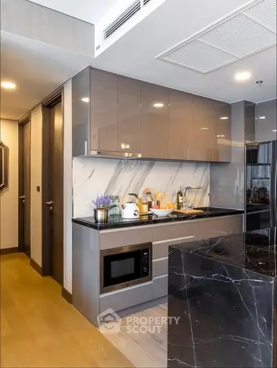 Modern kitchen with sleek cabinets and marble backsplash in luxury apartment.