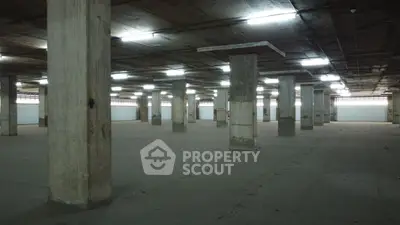 Spacious industrial warehouse with concrete pillars and ample lighting.