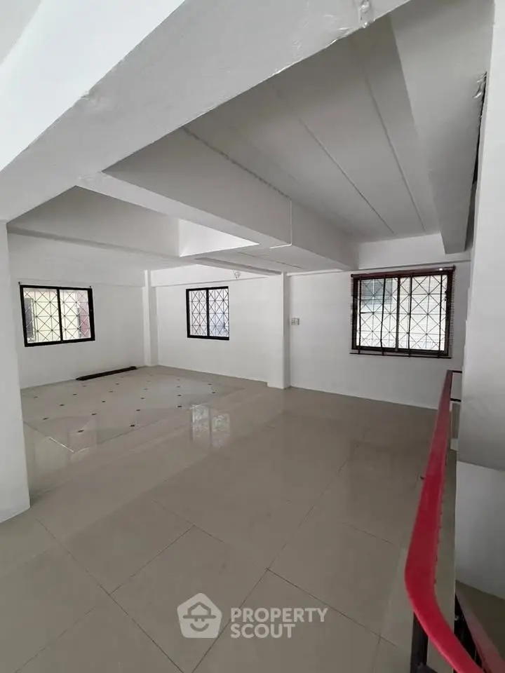 Spacious open-plan interior with tiled flooring and large windows, ideal for versatile living arrangements.