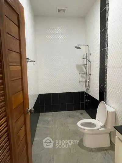 Modern bathroom with sleek black and white tiles and a rainfall showerhead.