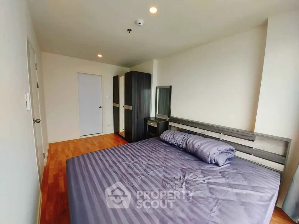Spacious bedroom with modern furniture and wooden flooring in a stylish apartment.
