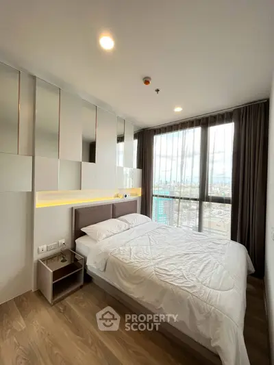Modern bedroom with large window offering stunning city view, featuring sleek design and cozy ambiance.