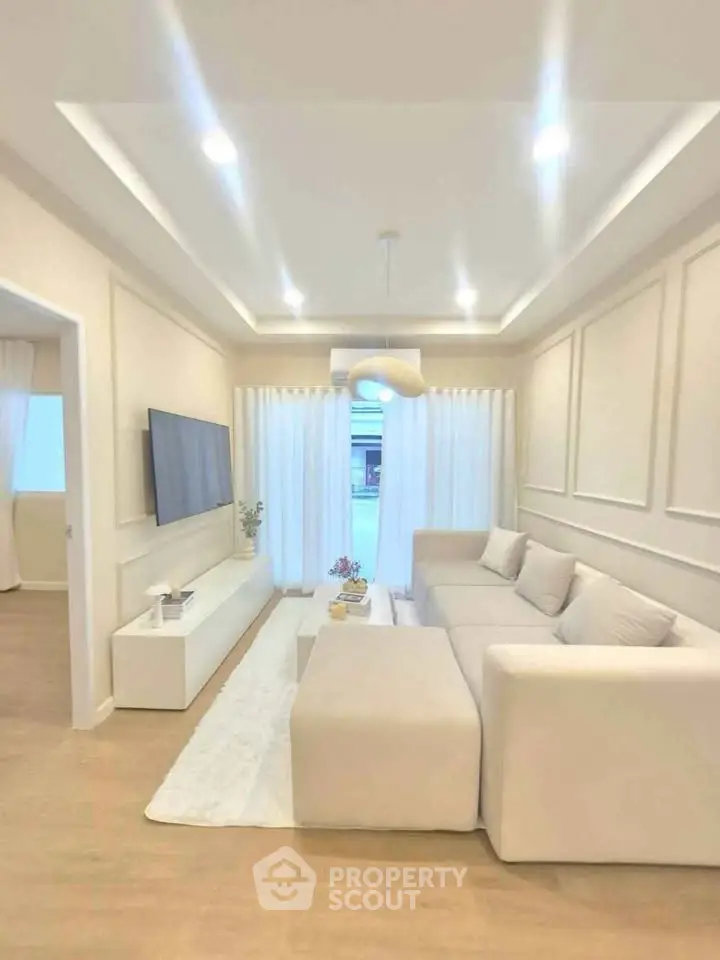 Elegant modern living room with cozy white sofa, sleek TV setup, and soft ambient lighting.