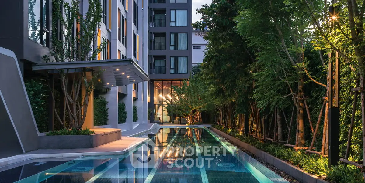 Luxurious modern apartment building with stunning pool and lush greenery.