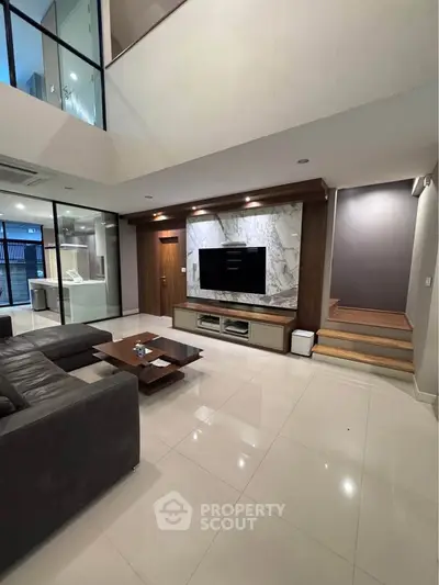 Luxurious modern living room with high ceilings, sleek furniture, and elegant marble TV wall.