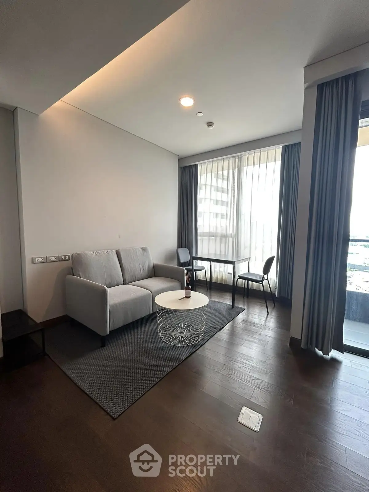 Modern living room with sleek furniture and large windows offering city views.